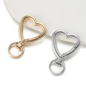 Macro view of gold and silver heart-shaped lobster clasps on marble surface