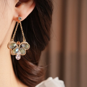 Macro detail of vintage gold drop earrings featuring iridescent crystals and floral cluster