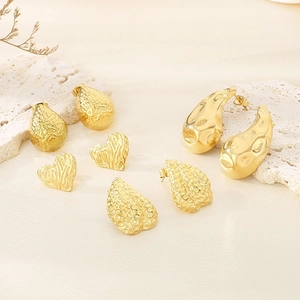 Golden geometric earrings set with leaf texture and hammered patterns on coral