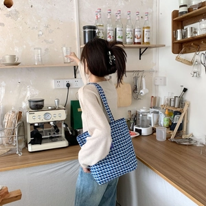 Detailed knit texture of blue plaid woven tote bag shown in cafe setting