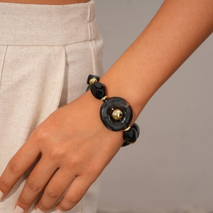 Detail view of a black acrylic beaded bracelet with golden metal spacers on a wrist