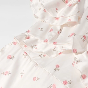 Gros plan d'une robe fleurie crème en satin soyeux avec des motifs de roses roses