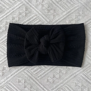 Close-up of black cable knit nylon baby headband with a decorative oversized soft bow