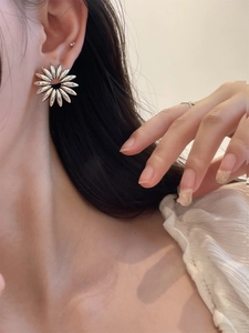 Detailed close-up of a model wearing elegant silver hollow-out flower petal stud earrings