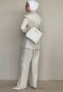 Detail view of the sleek white blazer collar and high-waisted wide-leg trousers ensemble