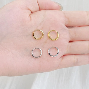 Detail of octagonal geometric hoop earrings in polished silver and gold finish