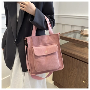 Detail of pink corduroy tote bag showing front flap pocket and soft ribbed fabric texture