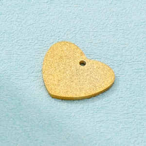 Macro view of gold frosted heart-shaped stainless steel pendant with textured finish