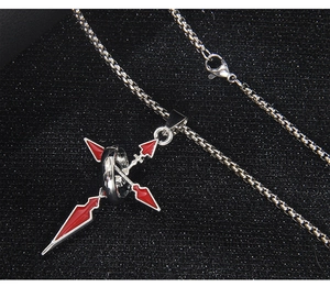 Macro detail of silver sword cross necklace with red enamel on textured background