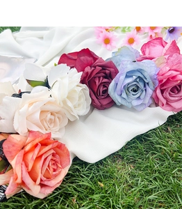 Detail of colorful fabric rose hair claws in white beige red blue and pink on grass