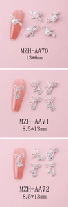 Macro shot of silver alloy bow nail charms with pearls and rhinestones on pink display