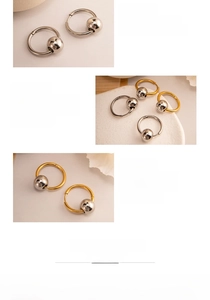 Détail de boucles d'oreilles créoles en argent et or avec boules métalliques décoratives