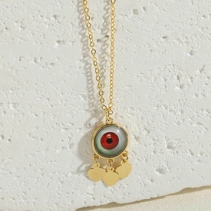 Detail of evil eye pendant with green eye pattern and hanging golden heart charms