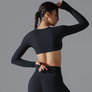 Dettaglio del crop top nero a maniche lunghe e leggings sportivi con finitura opaca liscia