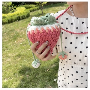 Detail of pink strawberry crochet bucket bag with green leaf top and mini charms