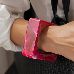 Close-up of a bold square resin bangle with pink and white marble pattern on a wrist
