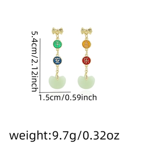Detail shot of long tassel earrings featuring golden bow and green bean pendant charms
