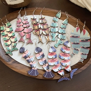 Detailed macro view of articulated wooden fish earrings with ethnic prints in a tray