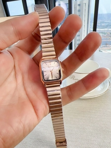 Close-up of a women's square rose gold quartz watch featuring a sunray dial and metal band