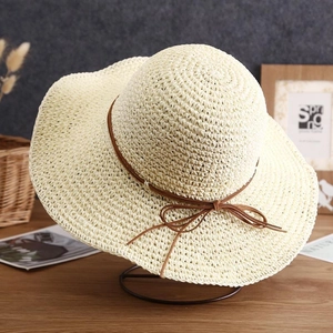 Detailed texture of woven straw sun hat featuring a delicate brown ribbon bow decoration
