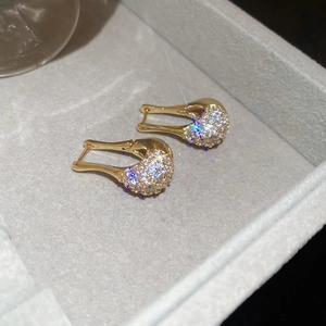 Vue macro de boucles d'oreilles dorées en U avec zircons sur plateau à bijoux
