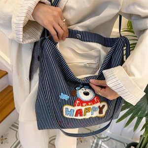 Detail showing magnetic buckle and inner zipper pocket of blue striped canvas bag