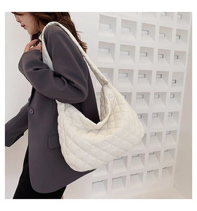 Close-up of white quilted puffer shoulder bag showing texture and stitching detail