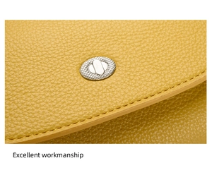 Close-up of yellow lychee grain leather texture with silver oval metal twist lock detail