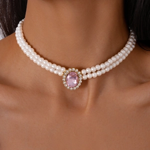 Macro shot of double-layered pearl choker featuring a pink gemstone and crystal pendant