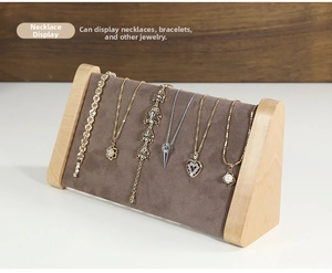 Detail view of solid wood jewelry stand with grey velvet surface for necklace display