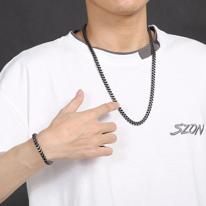 Close-up of a man wearing a black stainless steel cuban necklace and matching bracelet set