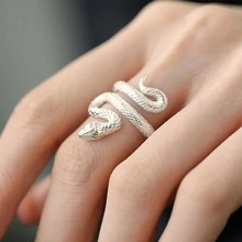Detailed close-up of a silver snake-shaped ring with textured scales and green stone eyes