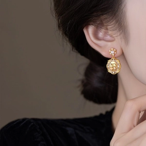 Close-up of vintage gold flower earrings with pearl and crystal embossed pendants
