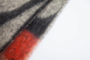 Macro texture of thick mohair-like scarf featuring grey, black, and orange wave patterns