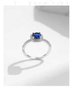 Macro detail of S925 sterling silver ring with deep blue halo stone and pavé diamonds