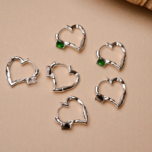 Detailed close-up of 925 silver heart hoop earrings with green, white, and black stones