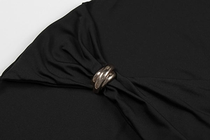 Close-up of bronze interlocking metal rings and elegant pleats on a black dress