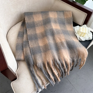 Close-up of soft gray and camel plaid scarf with long tassels on a beige chair