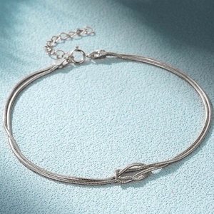 Detail of silver snake bone double-chain bracelet with knot charm and lobster clasp