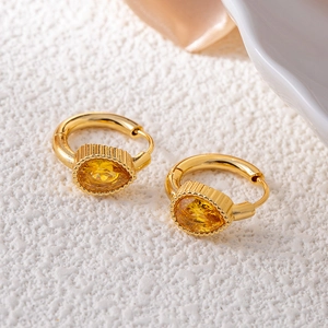Close-up of gold drop earrings with yellow pear-cut crystal and textured metal hoop
