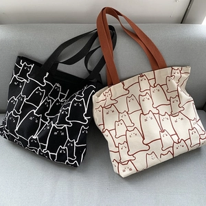 Detailed view of heavy canvas tote bags with cute cartoon cat prints in black and beige