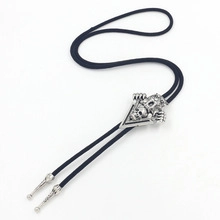 Detailed macro view of silver skull bolo tie with black braided leather rope and tips