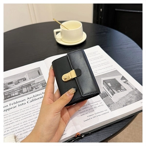 Close-up of black textured leather mini card holder with elegant gold metal clasp and flap