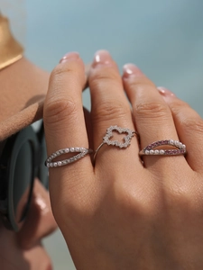 Close-up of silver stackable rings set featuring 5A zircons, pearls, and clover motifs