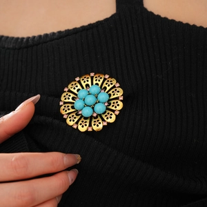 Close-up of vintage resin flower brooch with blue beads and pink crystals on black fabric