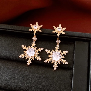 Detail of 18k gold plated snowflake earrings with crystal pavé in a black jewelry box