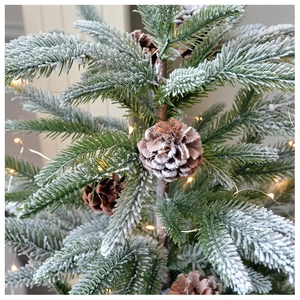 Close-up of frosted pine needles with realistic pinecones and warm LED fairy lights