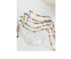 Macro shot of colorful faceted beads necklace with gold accents on a glass bowl