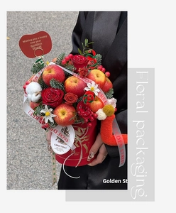 Close-up of Christmas gift bucket with red roses, cotton, and fresh apples in a festive box