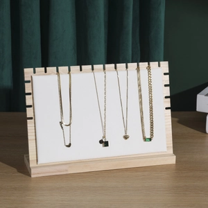 Close-up of wooden necklace display stand with white leather pads and gold jewelry